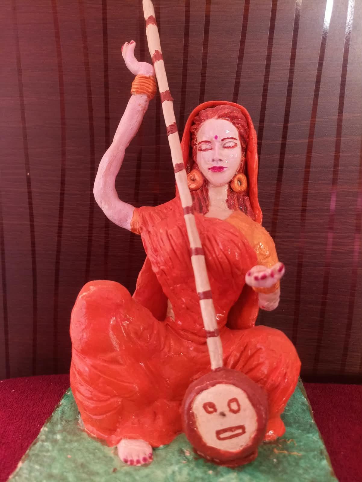 A hand-painted clay figure of a seated woman playing a stringed instrument, in saffron orange